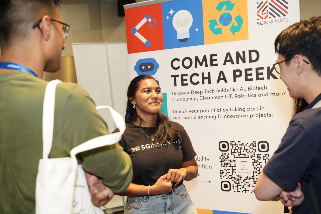 An exhibitor talking with visitors at the SGInnovate stall at UNICON 2026